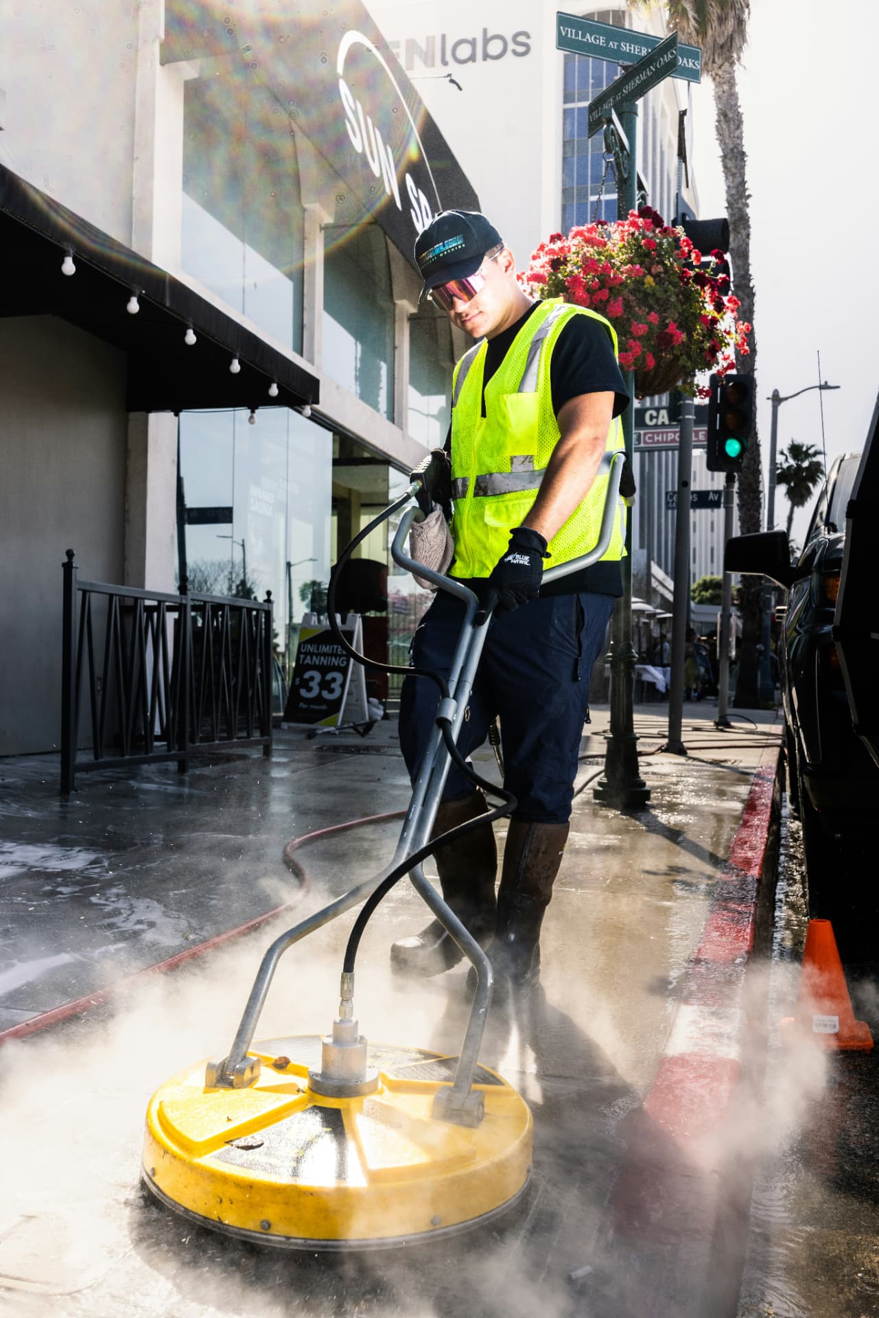Technician pressure washing a city sidewalk